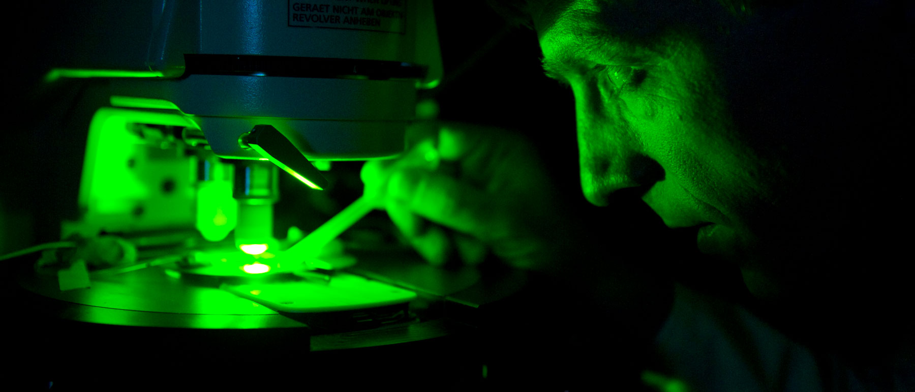 a faculty member conducting an experiment under a high-powered microscope