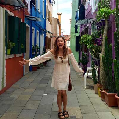 study abroad student smiling in the middle of a colorful italian street