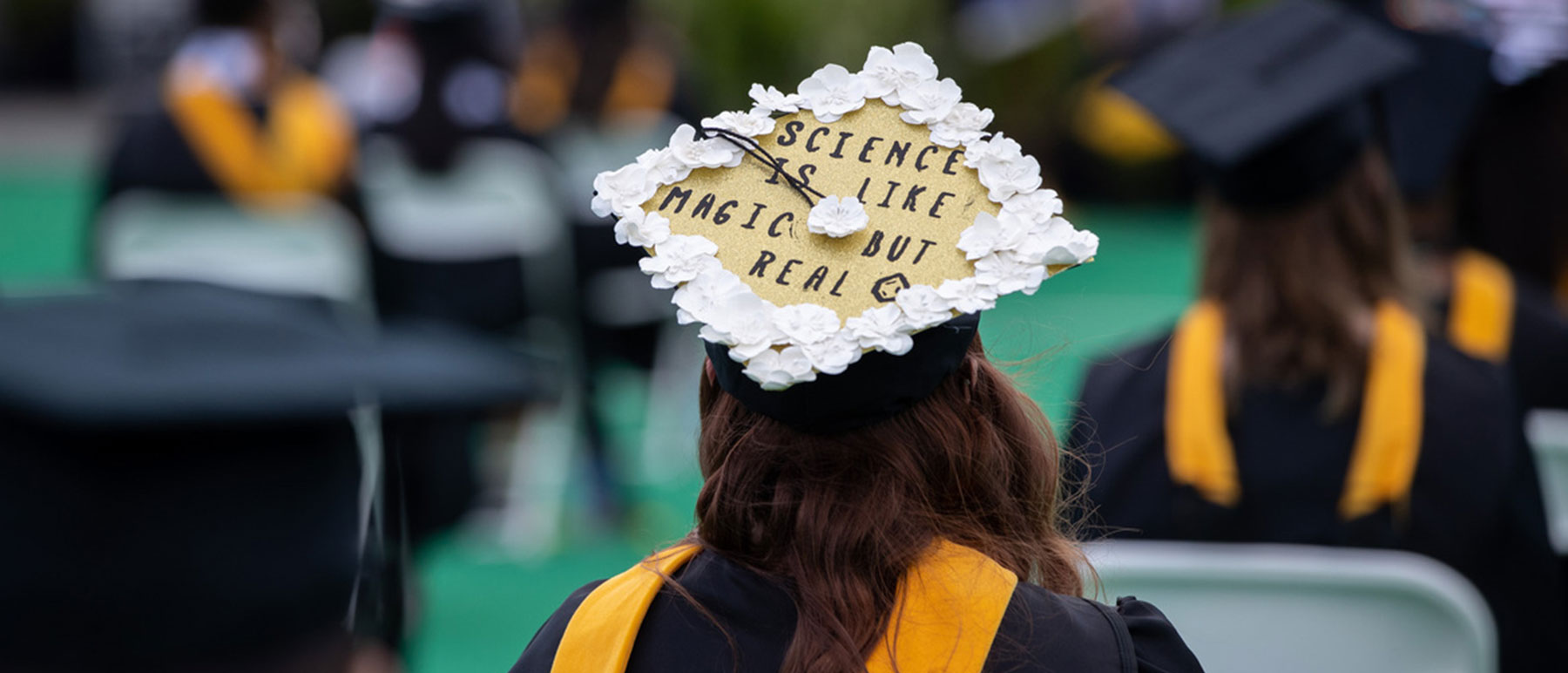 a v. c. u. student at a commencement ceremony wearing a graduation cap that reads 
