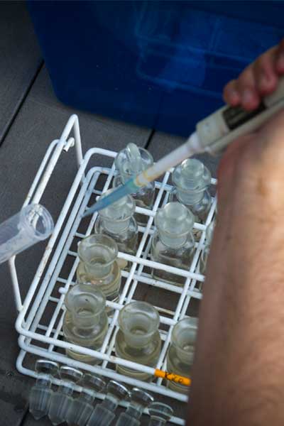 a student using a pipette to deposit measured liquid